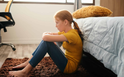 teen girl with autism sitting on the floor next to a bed
