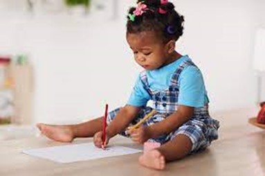 Toddler sitting on floor drawing