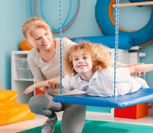 OT therapist and child with autism on a swing