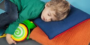A boy with a green shirt sleeping on a blue pillow