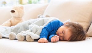 toddler wearing a blue top sleeping on the couch