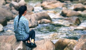 teen girl sitting on rocks by the river