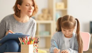 Female Positive behaviour support therapist with Little Girl During Art Therapy