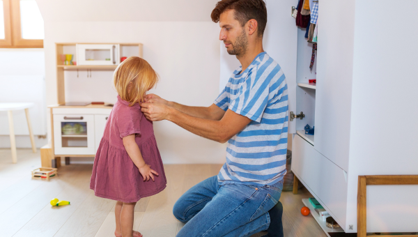 Father dressing his daughter who is a toddler